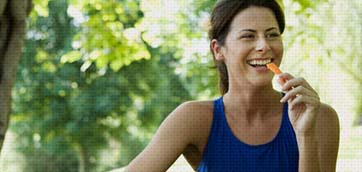 Woman smiling and eating a carrot